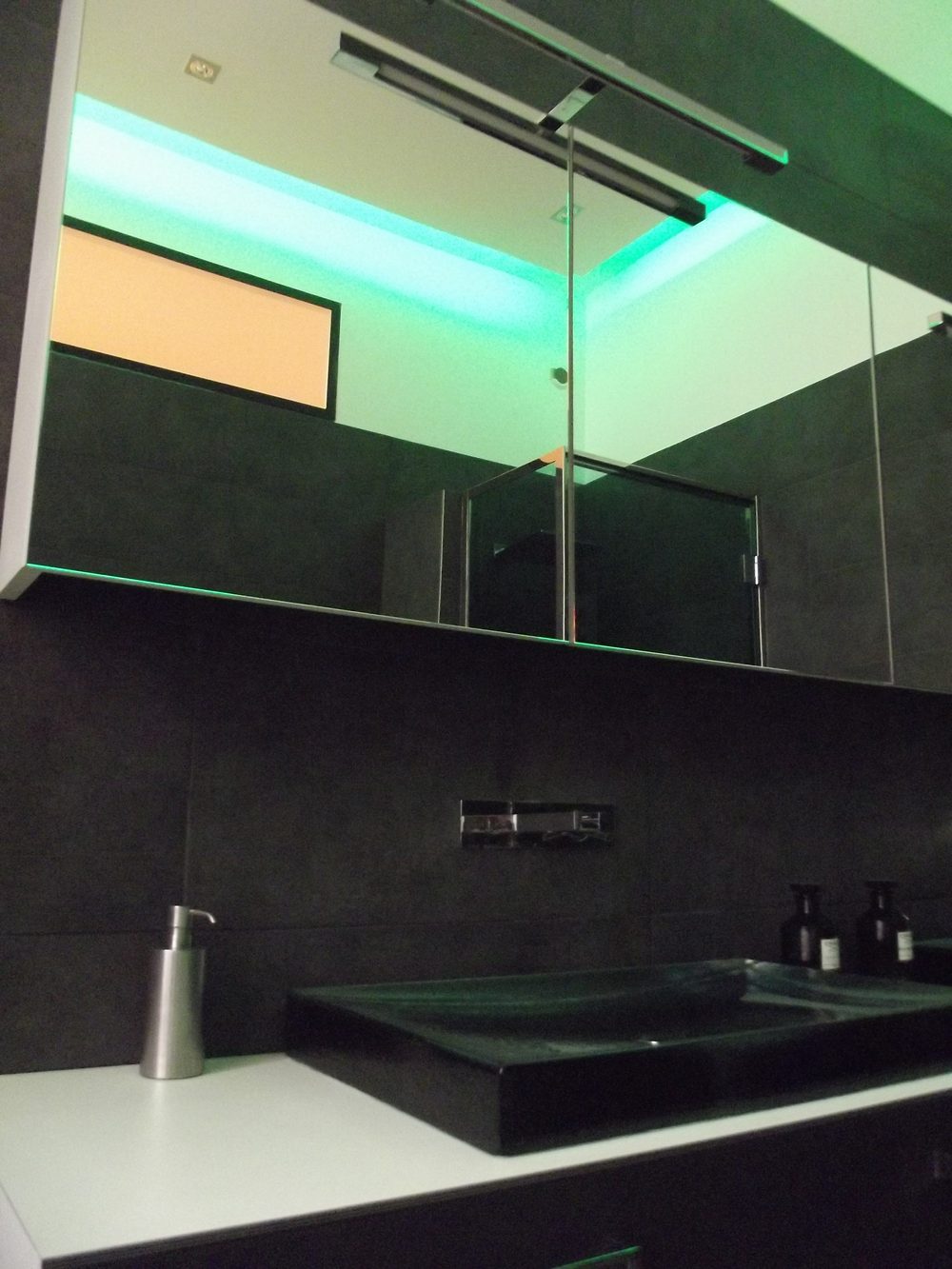 Armoire de toilette à miroirs éclairée, reflet de la gorge lumineuse verte et de la cabine de douche