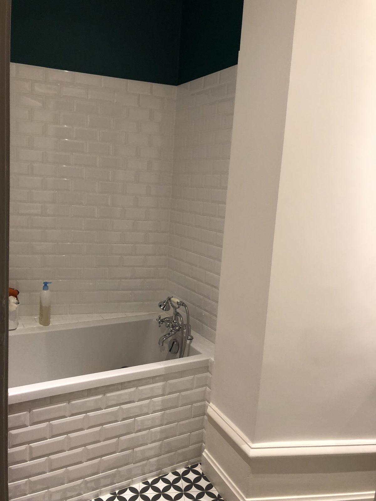 Baignoire remplacée avec tablier et murs en faïence blanche métro, peinture vert profond au-dessus