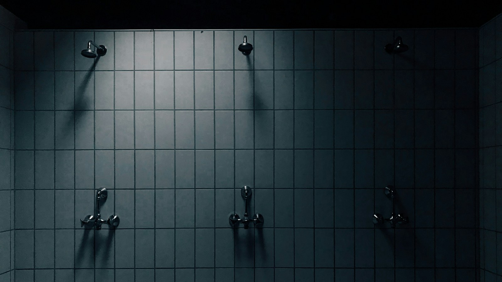 Douche carrelée de couleur grise avec paroi vitrée fixe et évacuation au sol