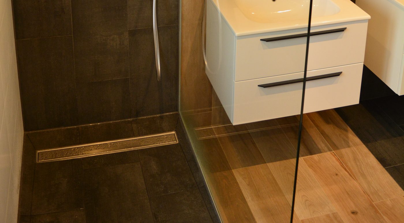 Douche à l'italienne avec caniveau inox et carrelage noir grand format, paroi de verre fixe