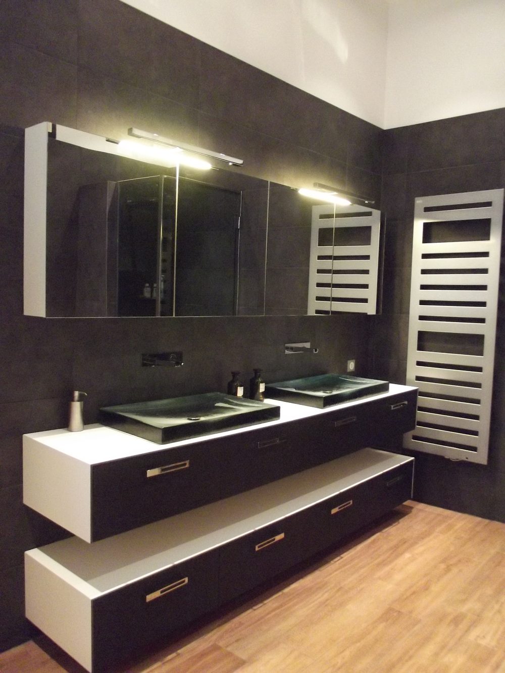 Meuble double vasque suspendu sur deux niveaux, armoire de toilette à miroirs éclairée et radiateur sèche-serviettes, sol imitation parquet