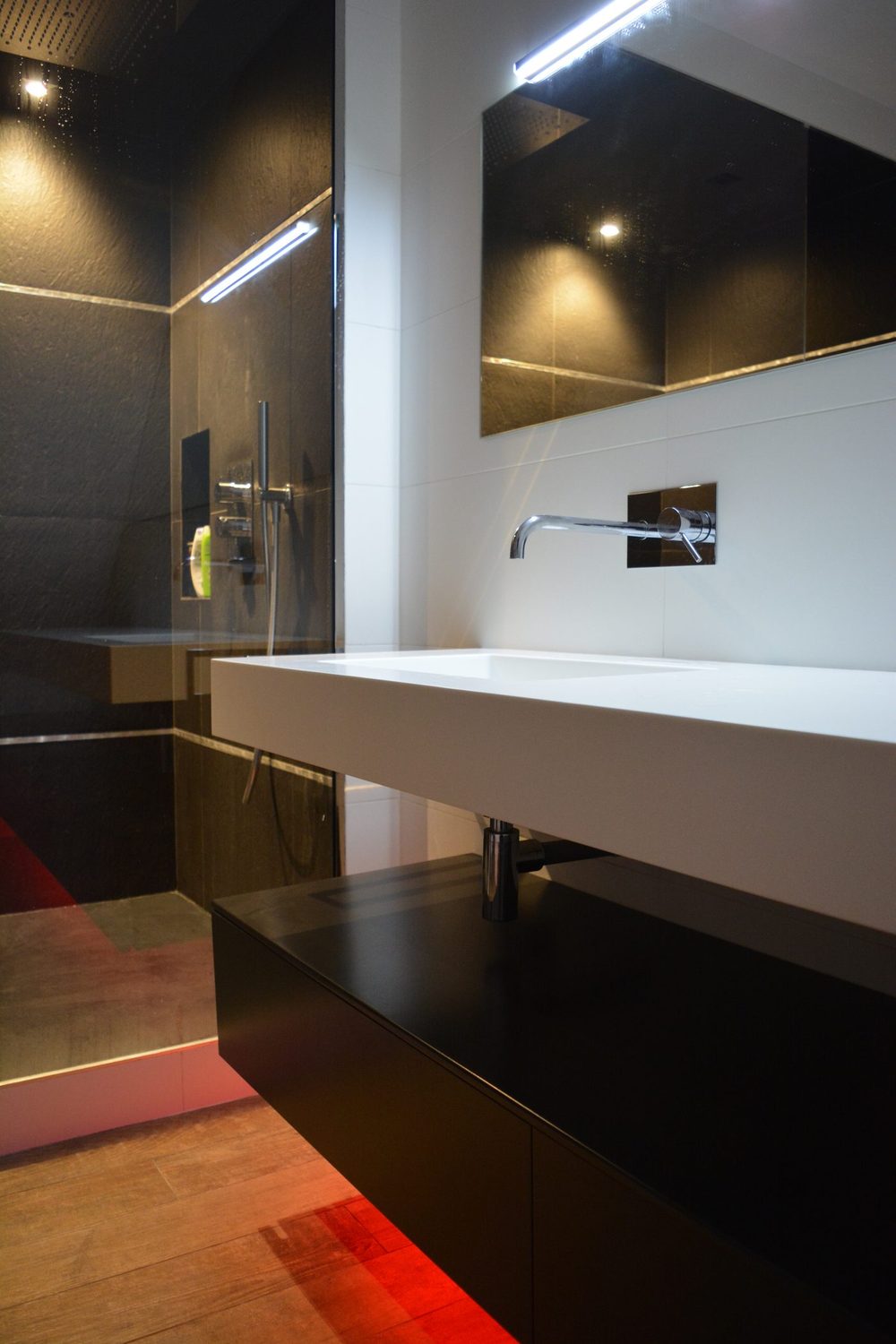 Plan vasque blanc et meuble noir suspendu à côté de la douche à l'italienne noire