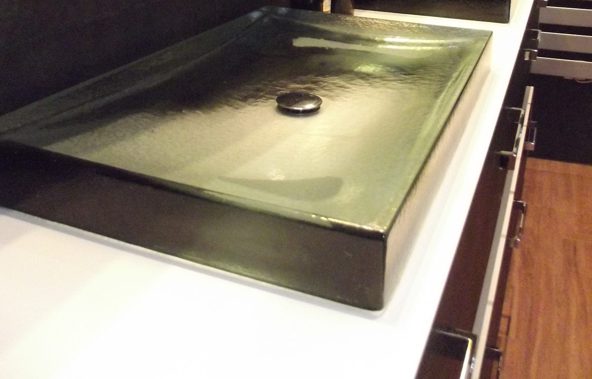 Vasque rectangulaire en verre coulé teinté vert posée sur un plan blanc