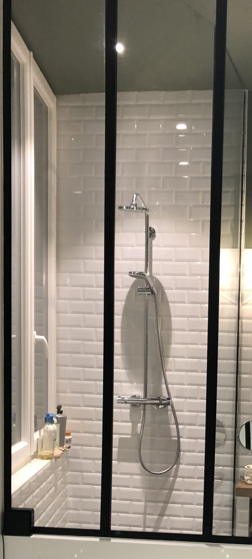 Verrière noire séparant la chambre de la salle d'eau, colonne de douche thermostatique et faïence métro